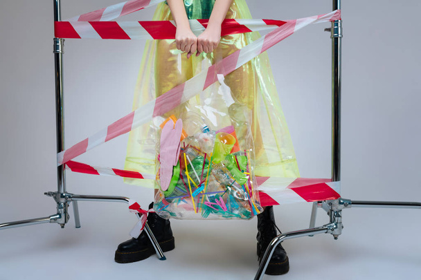 Mujer con botas con bolsa llena de pajitas y tazas de plástico
 - Foto, imagen