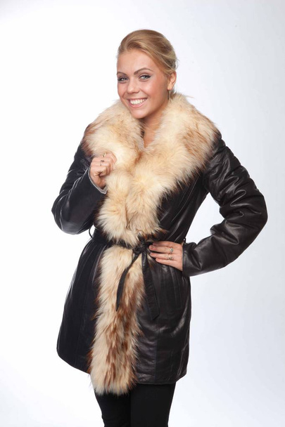 Young woman in a black leather coat with a fur hood - 写真・画像