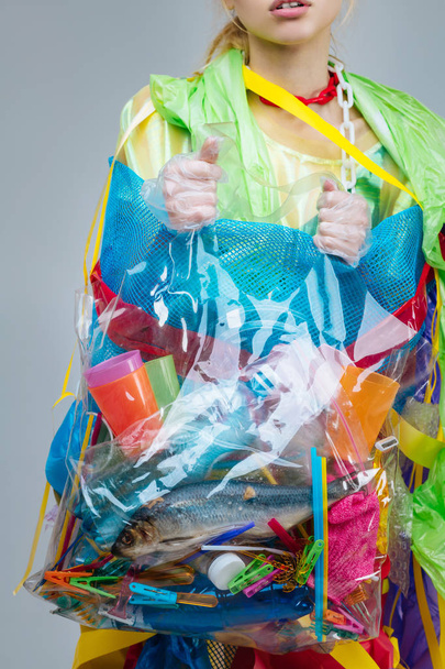 Model holding bag with plastic and fish realizing ocean pollution - Φωτογραφία, εικόνα