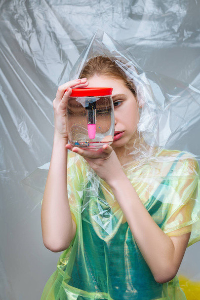 Model posing for ecology campaign holding glass can with lip gloss - 写真・画像