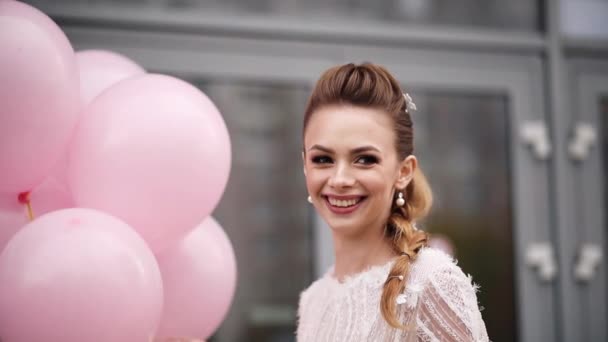Prachtig jong meisje met bloemen in haar met roze lucht ballonnen. - Video