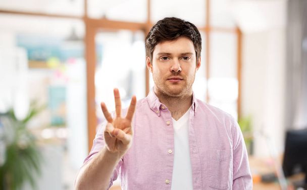 young man showing three fingers over office - Foto, Imagem