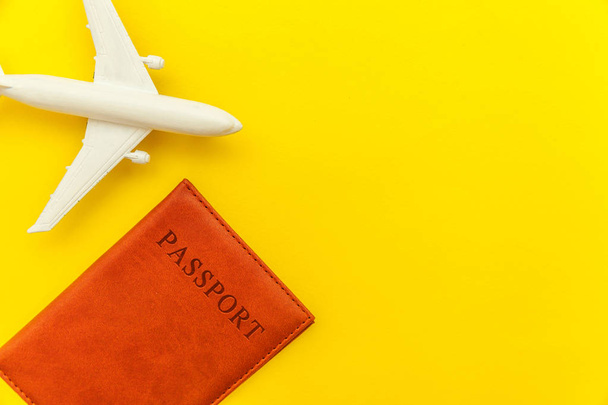Minimal simple flat lay travel adventure trip concept with plane and passport on yellow trendy modern background - Foto, imagen
