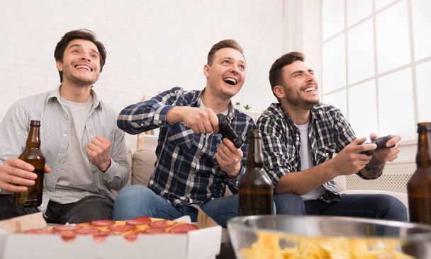 Excited men playing video game, having home party - Photo, Image