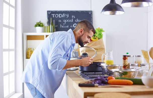 Lachende en vol vertrouwen chef-kok permanent in een grote keuken proeverij  - Foto, afbeelding