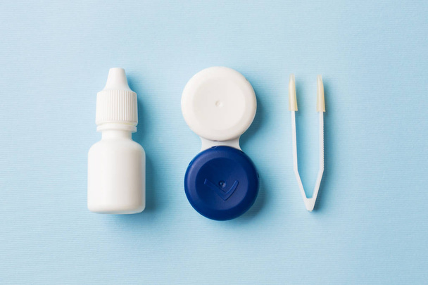 Contact lenses, tweezers and a container for storing lenses, containers for solution and moisturizing drops. Close up. Selective focus. - 写真・画像