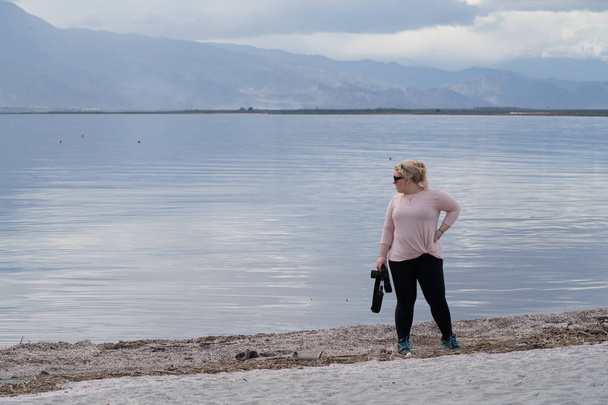 Vrouwelijke fotograaf staat op de kustlijn van de Salton zee, w - Foto, afbeelding