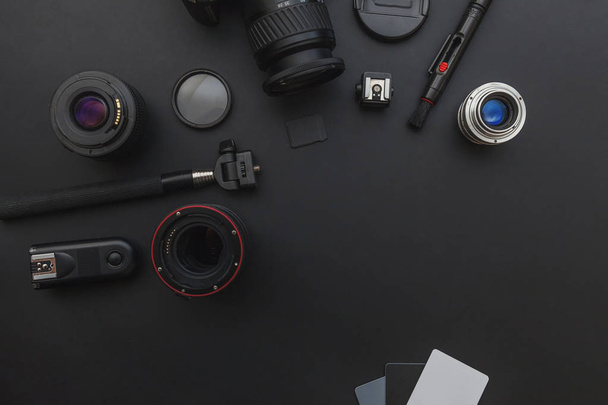 Рабочее место фотографа с системой камеры dslr, комплектом для очистки камеры, объективом и аксессуаром для камеры на темном фоне черного стола
 - Фото, изображение
