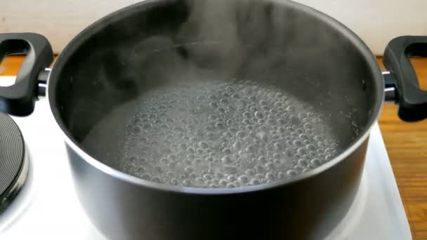 Cucina casalinga. Acqua bollente. L'acqua bolle con le bollicine in una pentola sul fornello elettrico in cucina
. - Filmati, video