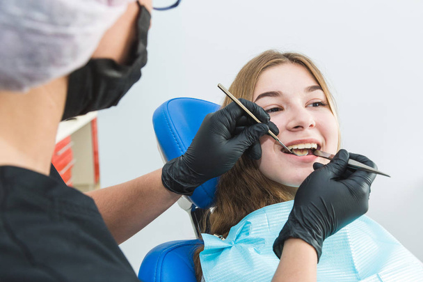 Dental clinic. Reception, examination of the patient. Teeth care. Young girl undergoes a dental examination by a dentist - Foto, Bild
