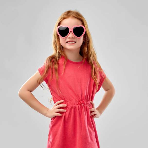 smiling red haired girl in heart shaped sunglasses - Foto, Imagen