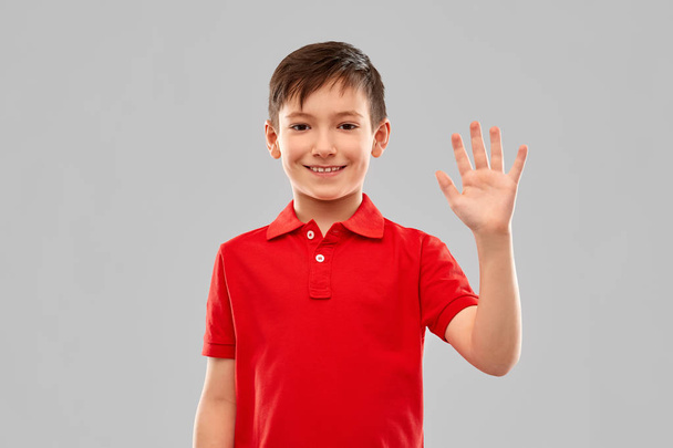 portrait of smiling boy in red t-shirt waving hand - Zdjęcie, obraz
