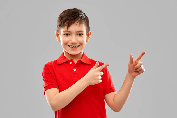 happy boy in red t-shirt pointing fingers aside - Фото, изображение