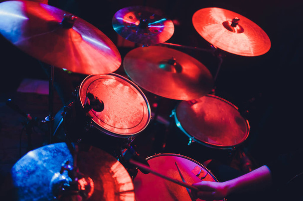 Drummer playing drum set at concert on stage. Music show. Bright scene lighting in club,drum sticks in hands. - Foto, imagen