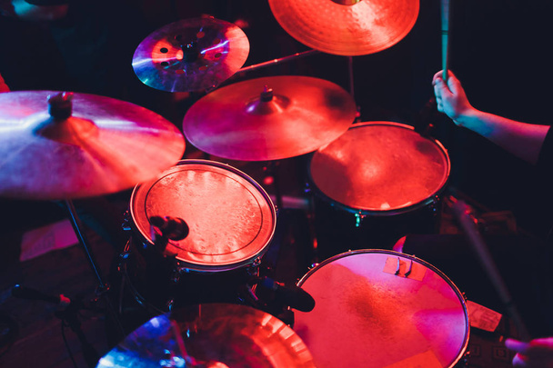 Drummer playing drum set at concert on stage. Music show. Bright scene lighting in club,drum sticks in hands. - Φωτογραφία, εικόνα