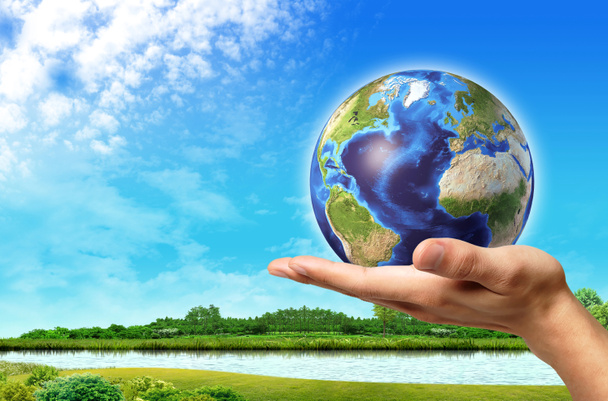 Man hand with earth globe on it and a beautiful green landscape - Photo, Image