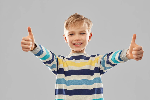 sorridente ragazzo a strisce pullover mostrando pollici in su - Foto, immagini