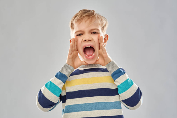 angry little boy in striped pullover screaming - Foto, Imagen