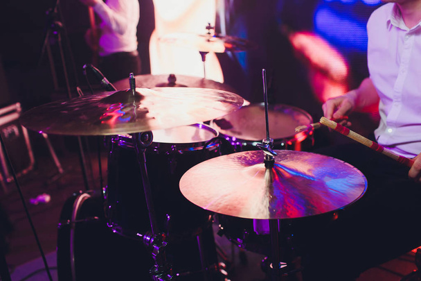 Барабанщик с барабанными палочками в руках, играющий на барабанах на сцене на черном фоне
. - Фото, изображение