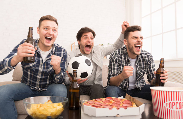Meta. Hombres felices viendo el partido de fútbol en casa
 - Foto, Imagen