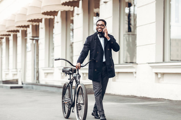 Businessman walking with bicycle and talking on phone - Фото, зображення