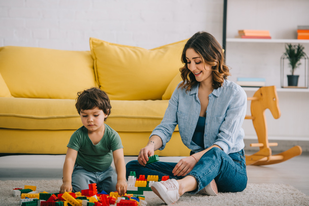 Mom and son playing with toy blocks in living room - Photo, Image