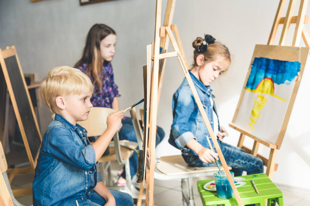 A group of preschool students and young teacher in drawing class paint in gouache. mixed race schoolgirl afroamerican and boy. Artwork - Fotografie, Obrázek