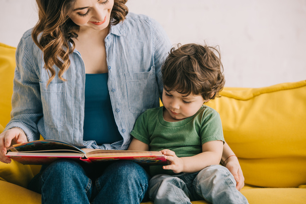 Cropped view of mother and son reading book together - 写真・画像
