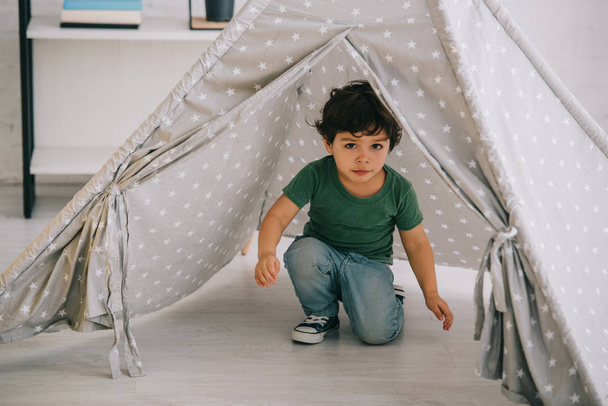 cute kid in jeans sitting in grey wigwam at home - Valokuva, kuva