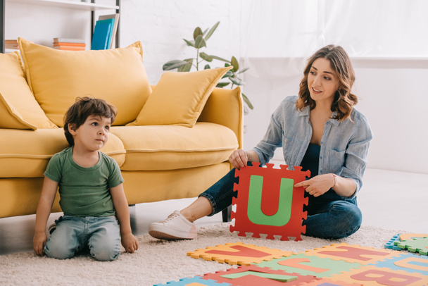 Sorrindo mãe e criança brincando com tapete de quebra-cabeça alfabeto
 - Foto, Imagem