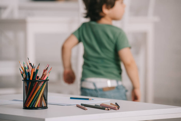 Selective focus of child near table with color pencils - Photo, Image