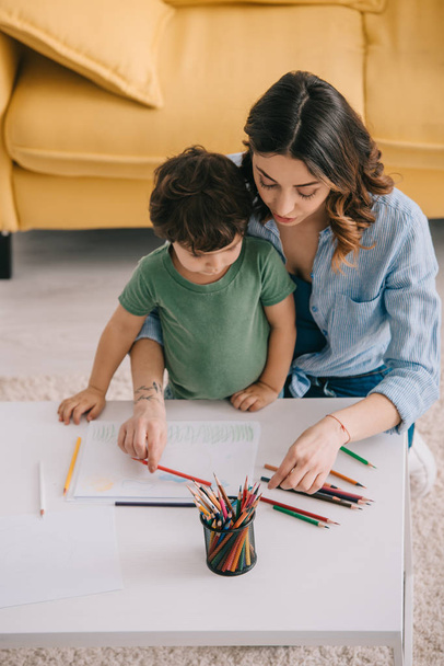 Mother and son drawing with color pencils in living room - Foto, immagini