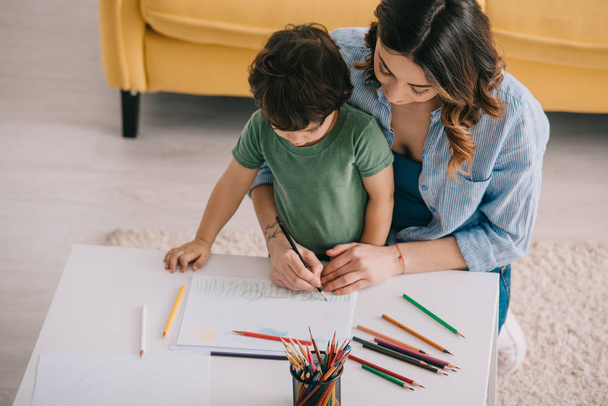 Mother and son drawing with color pencils in living room - Φωτογραφία, εικόνα