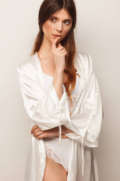 Sexy woman in white robe and white lingerie. Studio photo session - Foto, Bild