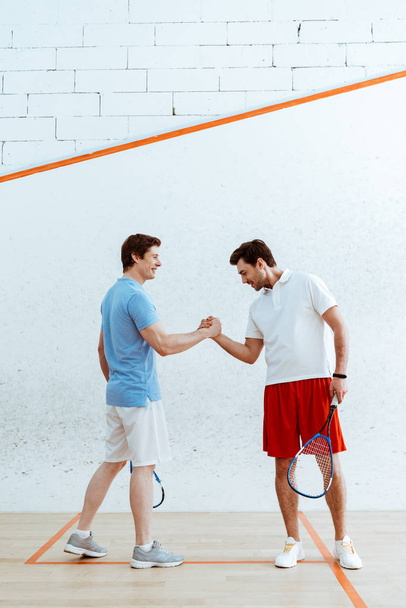 Two squash players with rackets shaking hands and looking at each other - 写真・画像