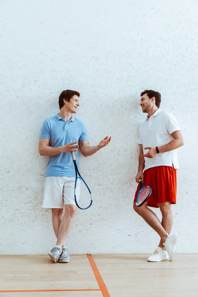 Squash oyuncularının birbirleriyle konuştuklarını ve birbirlerine baktıklarının tam boy görünümü - Fotoğraf, Görsel