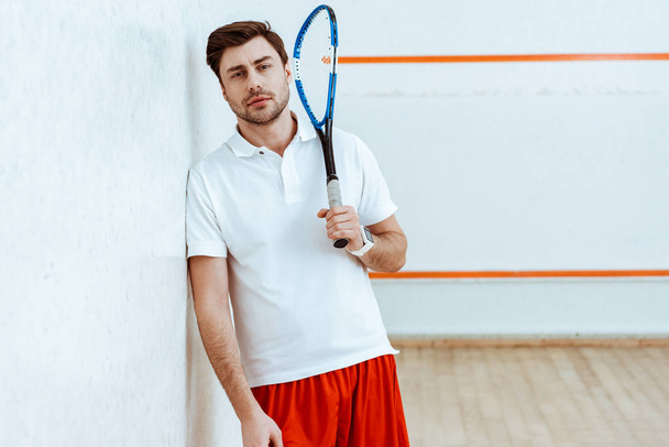 Bearded squash player holding racket and looking at camera - Foto, immagini