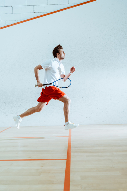 Vista completa del deportista con raqueta corriendo mientras juega squash
 - Foto, imagen