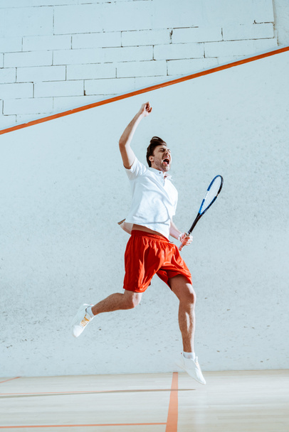 Full length view of happy squash player with racket showing yes gesture - Foto, afbeelding
