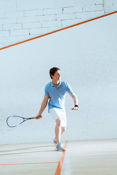 Full length view of concentrated sportsman in smartwatch playing squash - 写真・画像