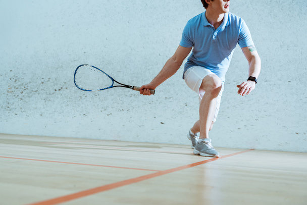 Partial view of sportsman in blue polo shirt playing squash - Фото, изображение