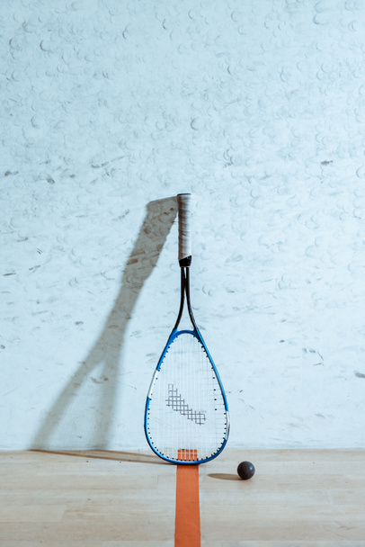 One squash racket and ball on wooden floor in four-walled court - Fotografie, Obrázek