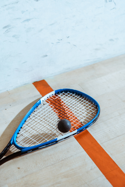 One squash racket and ball on wooden surface - Fotografie, Obrázek