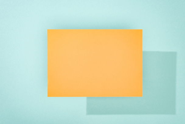 orange empty card with copy space and shadow on turquoise background - Foto, immagini