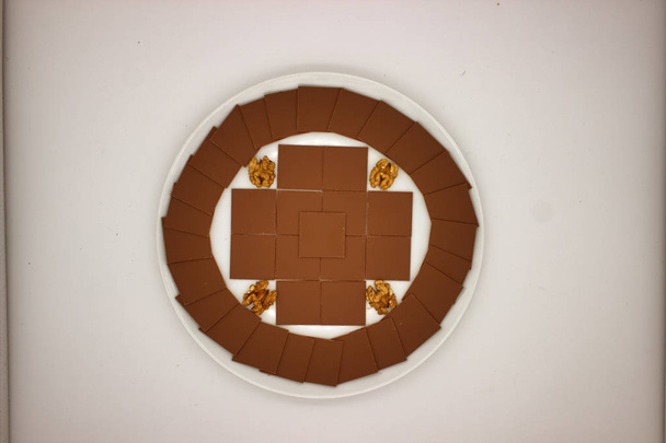 Quadrate aus dünner Schokolade werden in einem Kreis und einem Kreuz ausgelegt - Foto, Bild