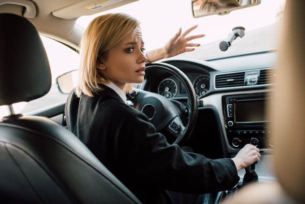 worried blonde woman gesturing while sitting in car  - Foto, afbeelding