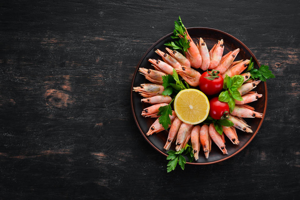 Shrimp with lemon in a plate on a black background. Top view. Free copy space. - Fotoğraf, Görsel