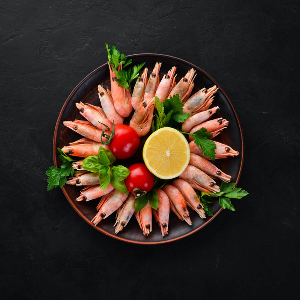 Shrimp with lemon in a plate on a black background. Top view. Free copy space. - Foto, Bild