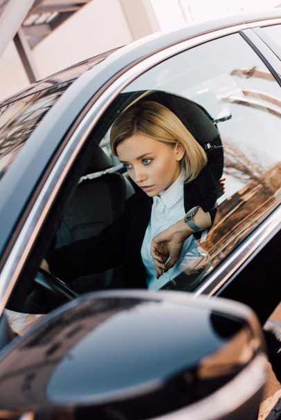 beautiful blonde woman holding steering wheel while driving car  - Фото, изображение