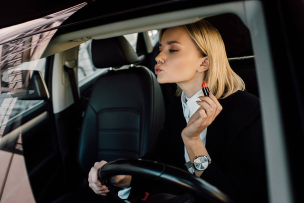 jolie femme blonde avec le visage de canard tenant rouge à lèvres dans la voiture
  - Photo, image